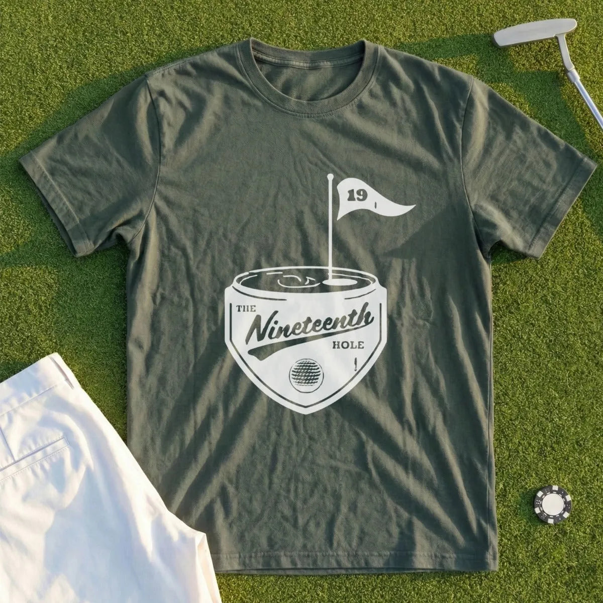 Dark green t-shirt with "The Nineteenth Hole" logo and golf accessories.