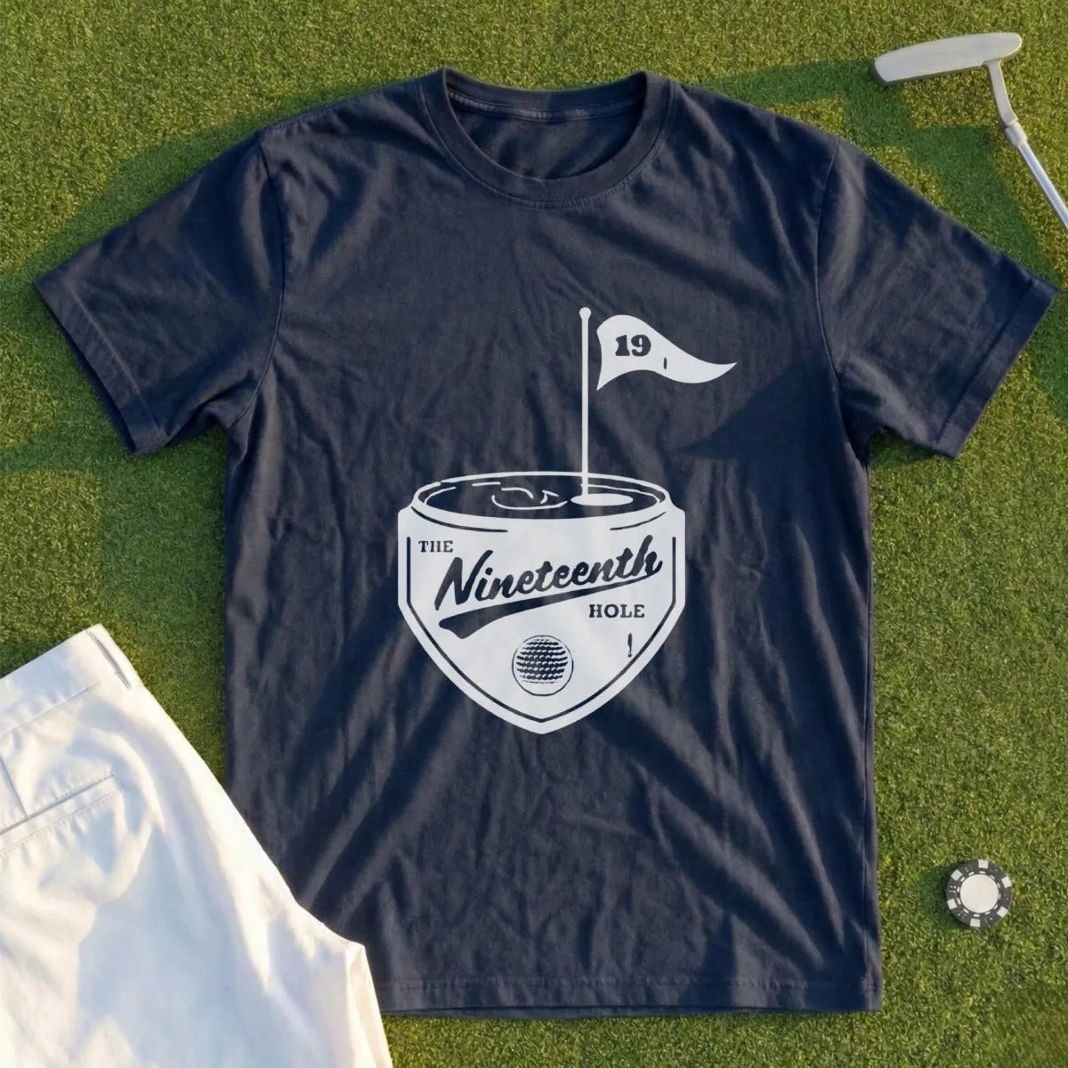 Dark navy t-shirt with "The Nineteenth Hole" logo on grass.