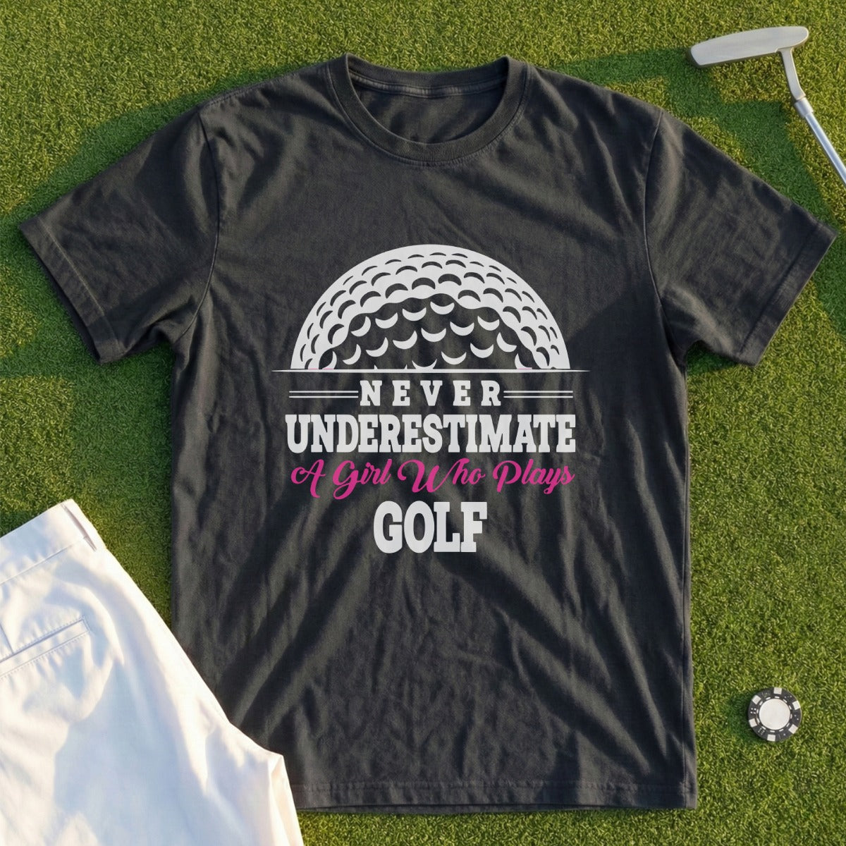 Black t-shirt with "Never Underestimate A Girl Who Plays Golf" text and golf ball graphic.