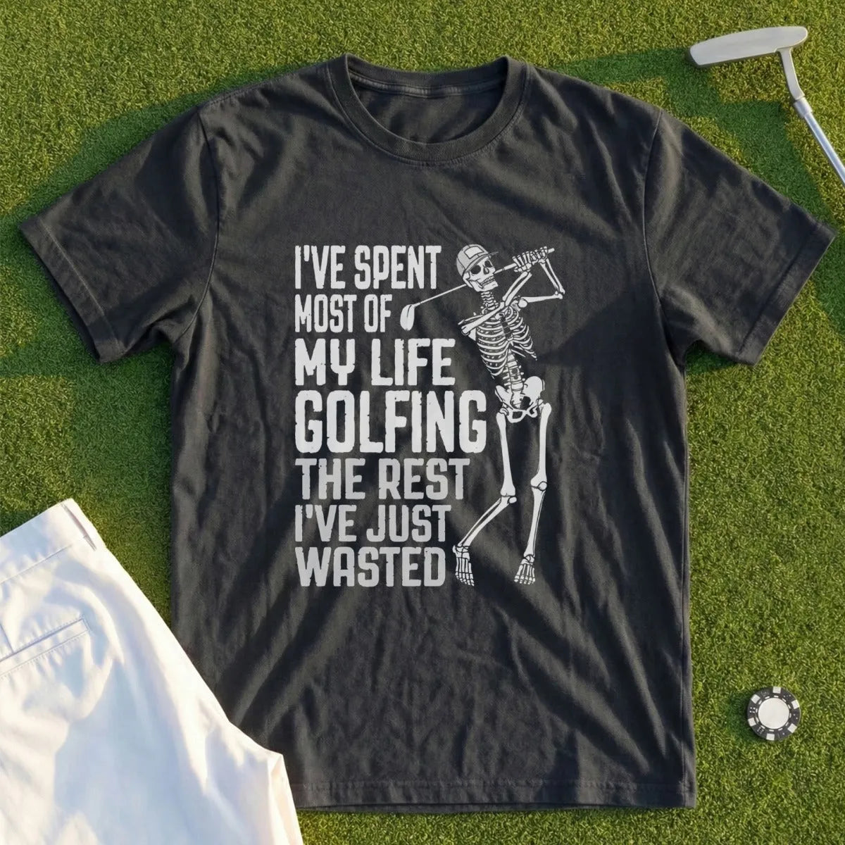 Skeleton golfer swinging club on dark t-shirt with text.
