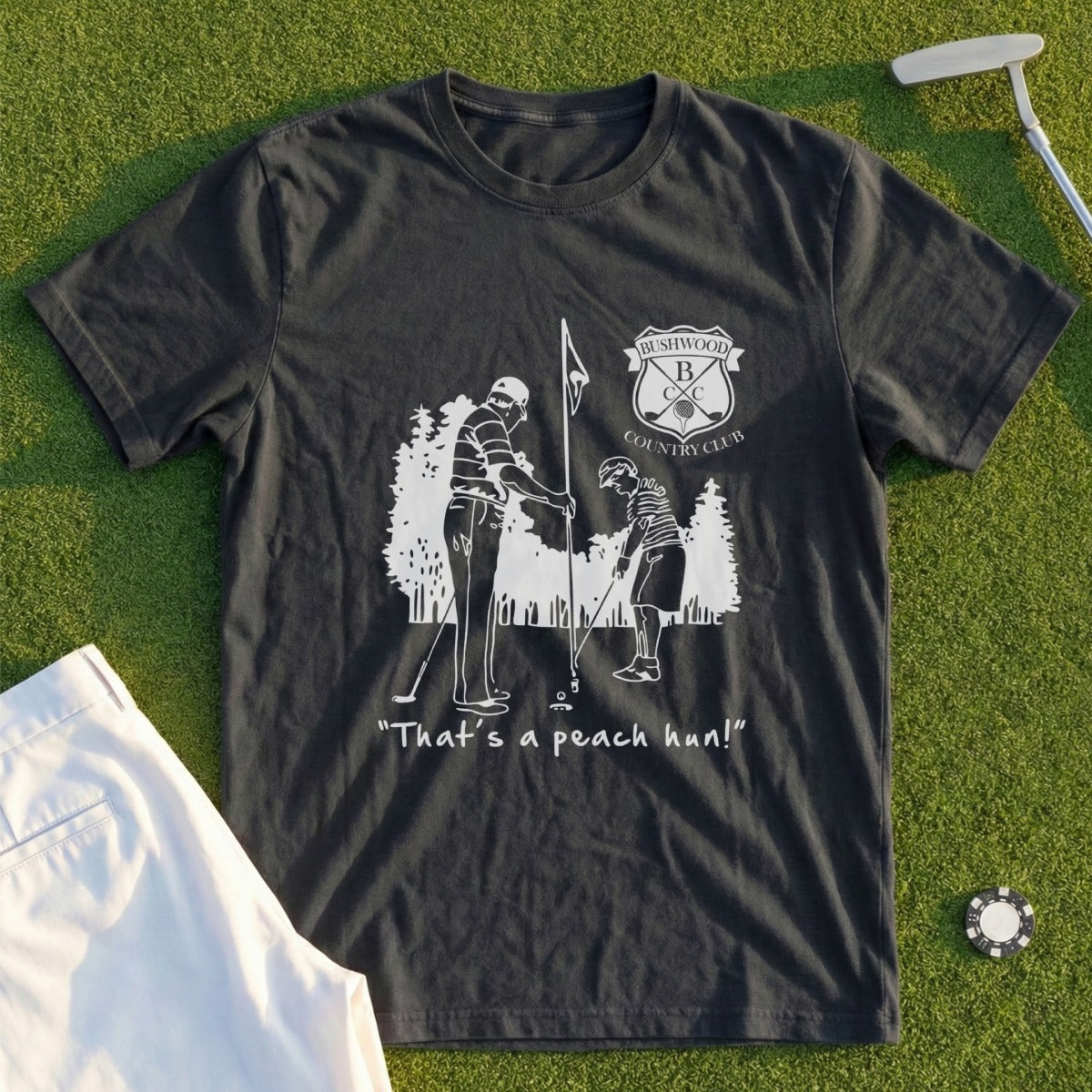 Dark t-shirt with a white graphic of two golfers and the text "That's a peach hun!"
