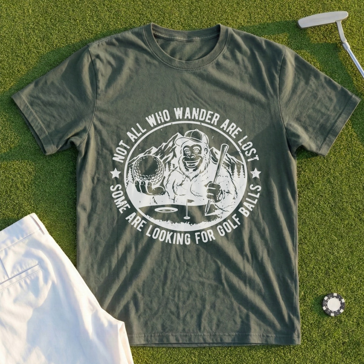 Green t-shirt with graphic of a Bigfoot-like character holding golf clubs and ball.