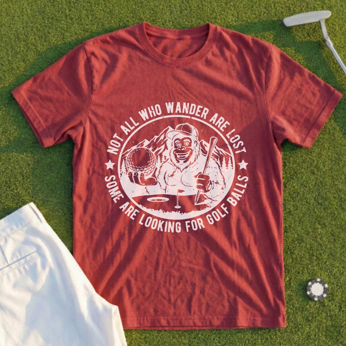 Burgundy t-shirt with a Bigfoot golfing graphic and text: "Not all who wander are lost, some are looking for golf balls."
