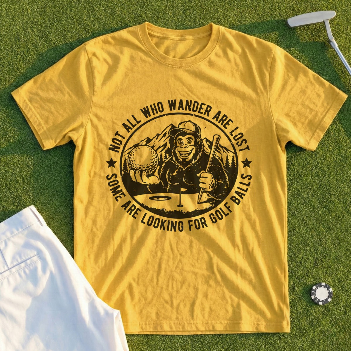 Yellow t-shirt with Bigfoot holding a golf ball and club, text reads "Not all who wander are lost, some are looking for golf balls".