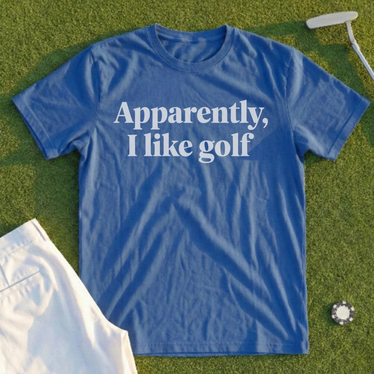 Blue t-shirt with "Apparently, I like golf" text, shown with golf accessories.