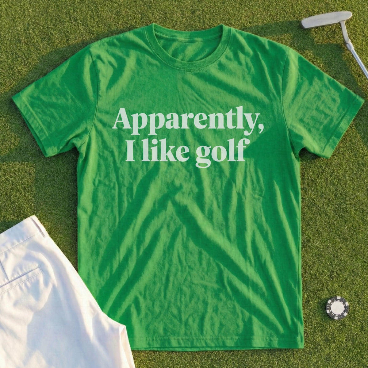 Green t-shirt with white text "Apparently, I like golf" on a golf course.
