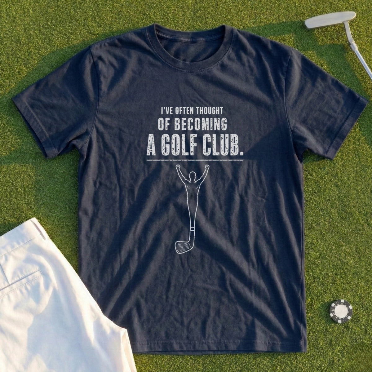 Navy t-shirt with text and golf club graphic on a grassy surface.