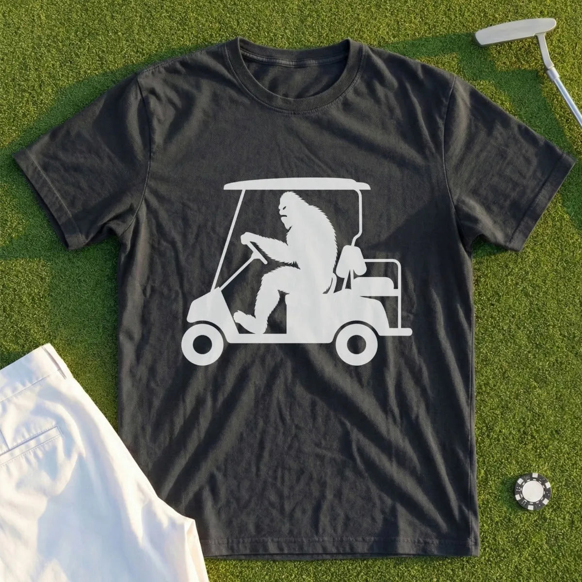 Bigfoot driving a golf cart graphic on a dark t-shirt.
