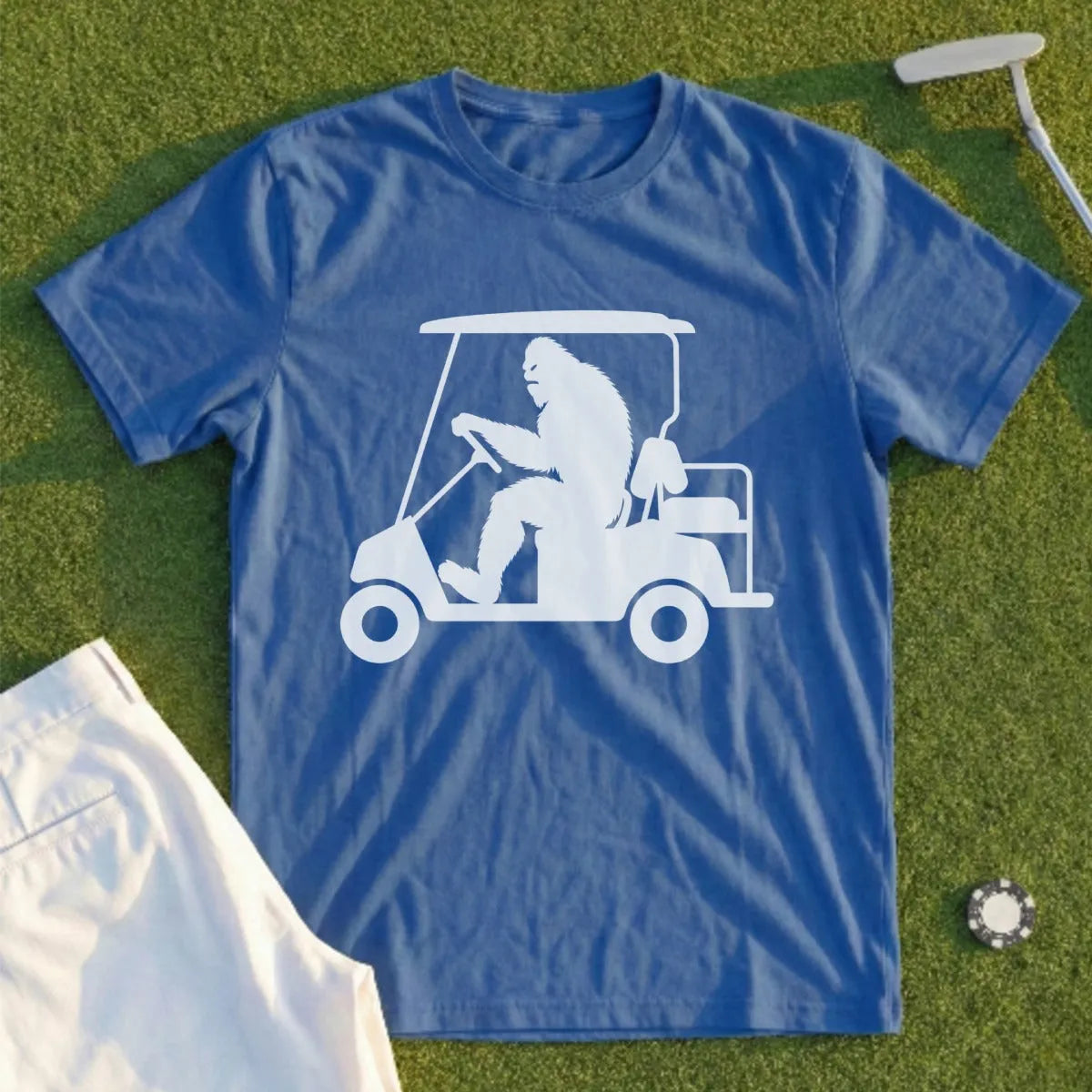 Blue t-shirt with a white graphic of Bigfoot driving a golf cart.