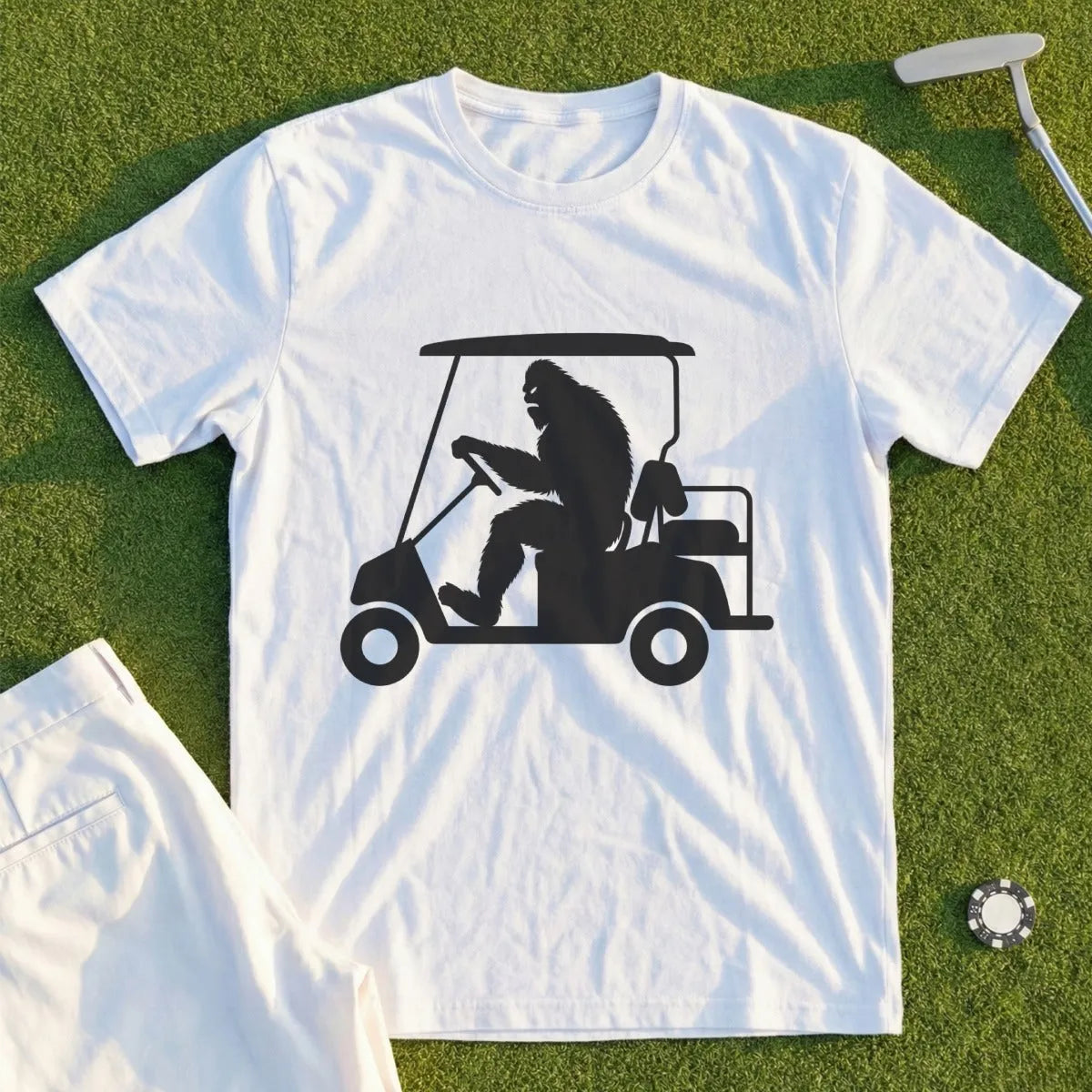 Bigfoot driving a golf cart graphic on a white t-shirt.