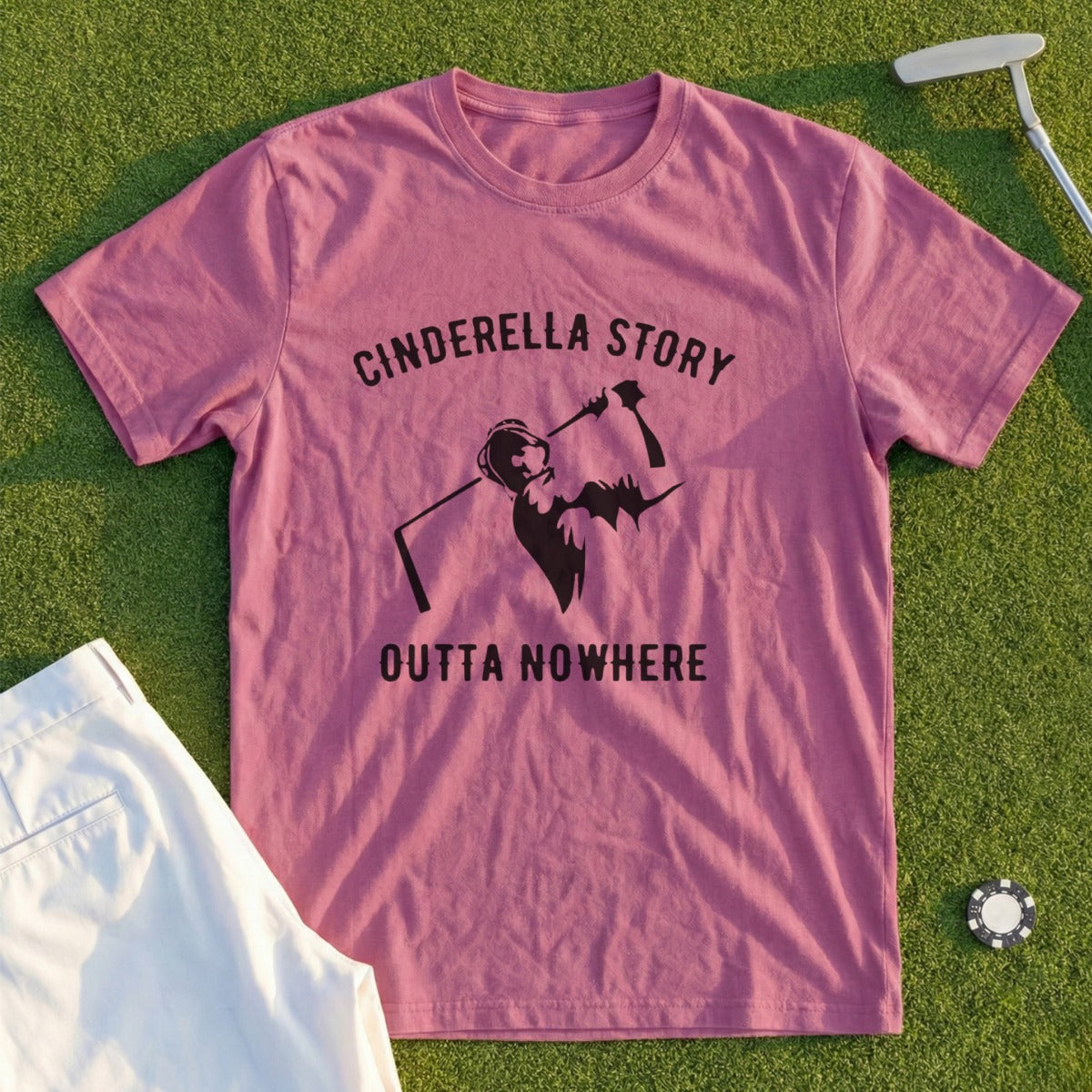 Pink t-shirt with "Cinderella Story Outta Nowhere" graphic on a golf course.