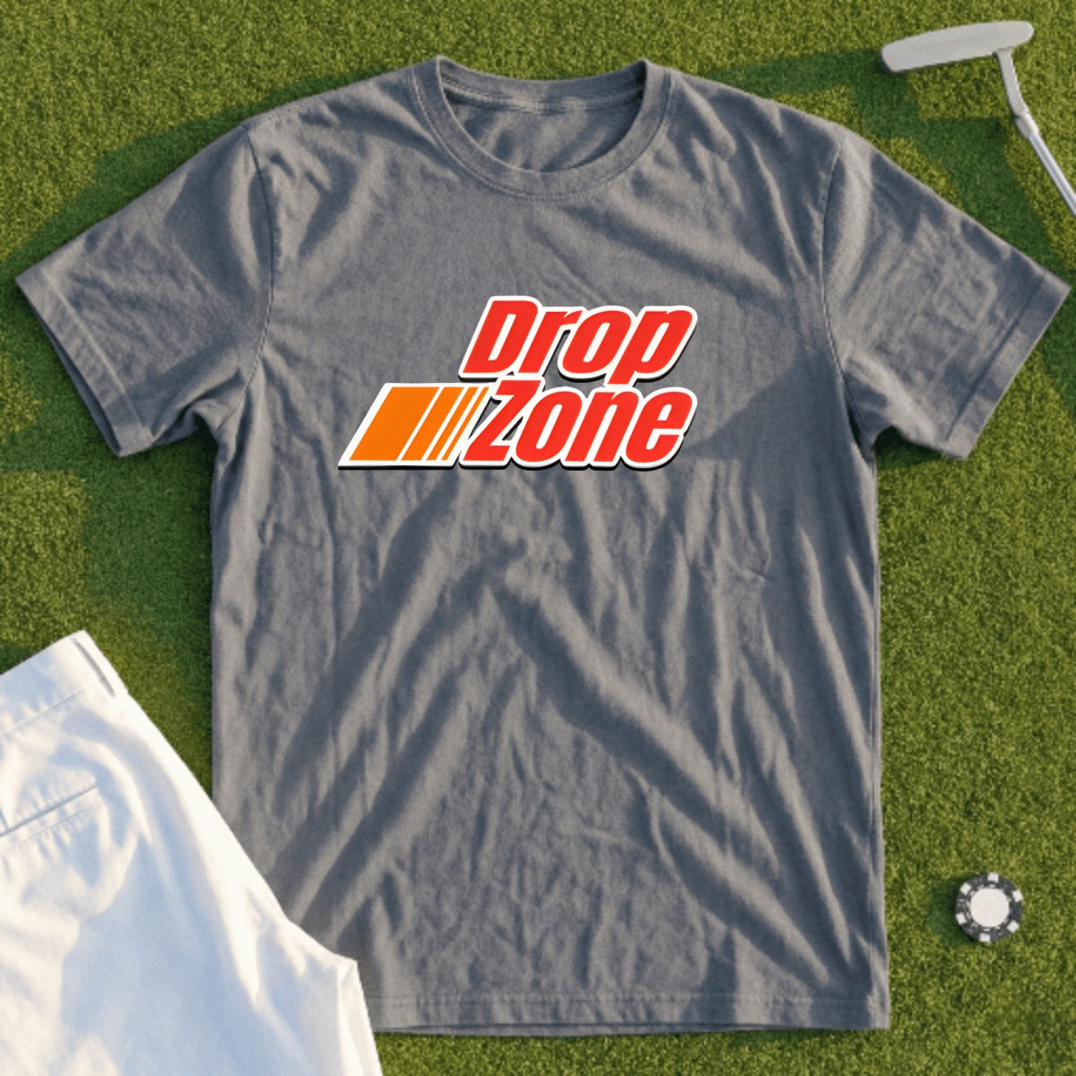 Grey t-shirt with "Drop Zone" text logo, laid on grass with golf items.