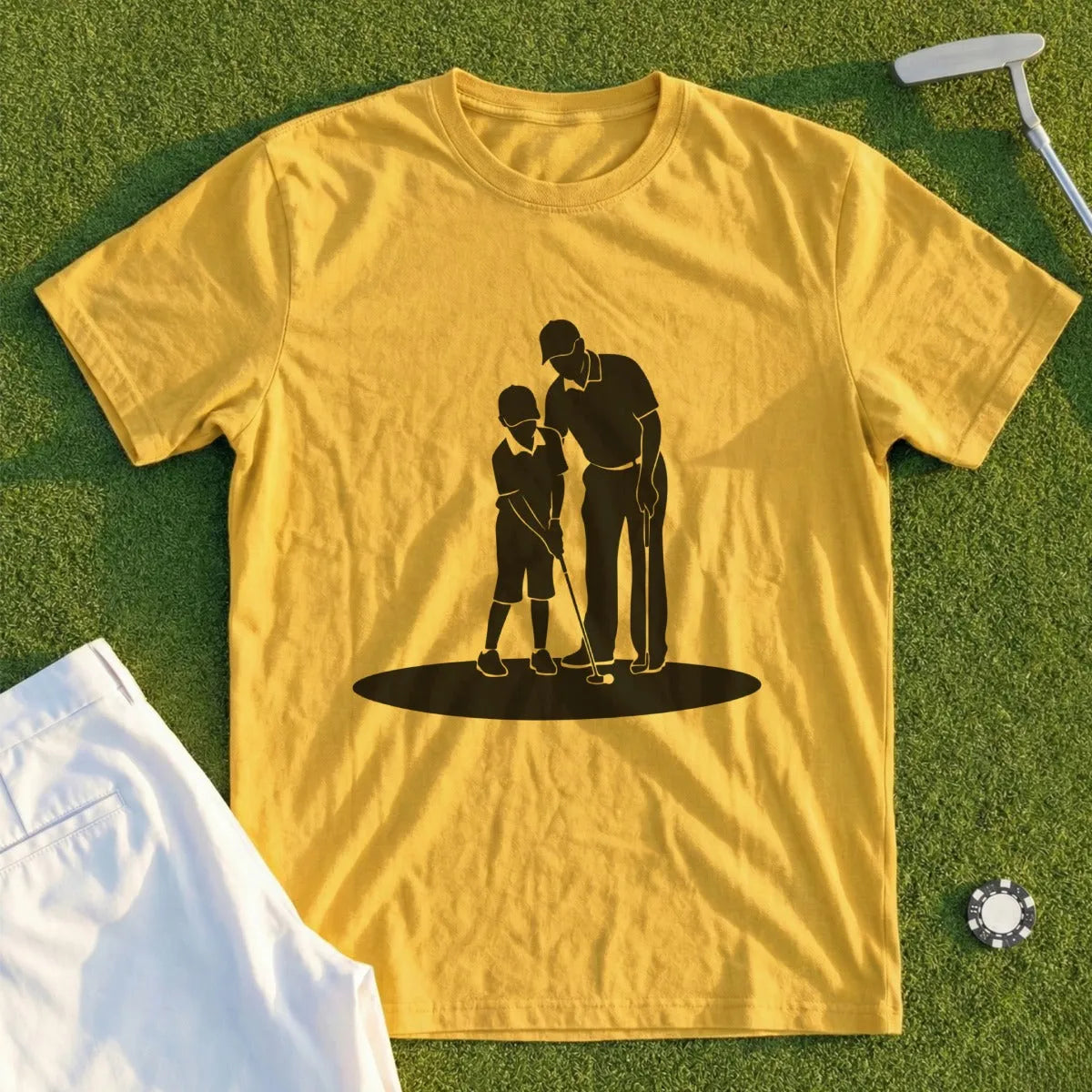 Yellow t-shirt with silhouette of golfer teaching child to putt on green grass.