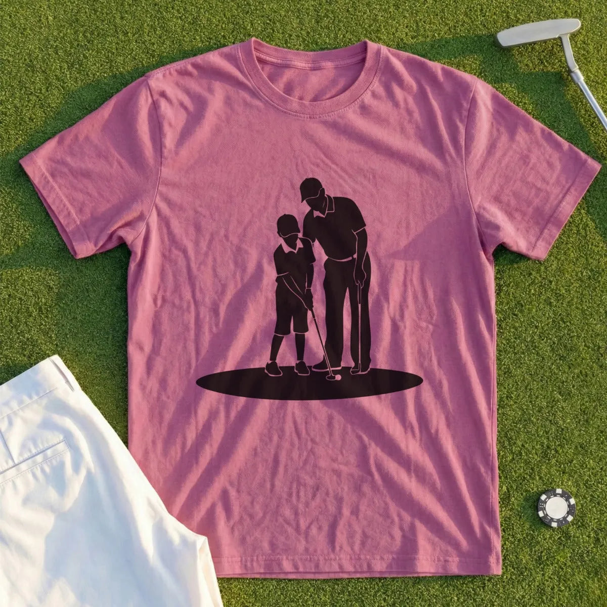 Black silhouette of a man teaching a child to golf on a pink t-shirt.