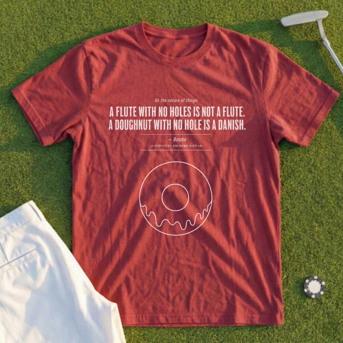 Maroon t-shirt with quote about flutes and doughnuts, golf tee and ball.