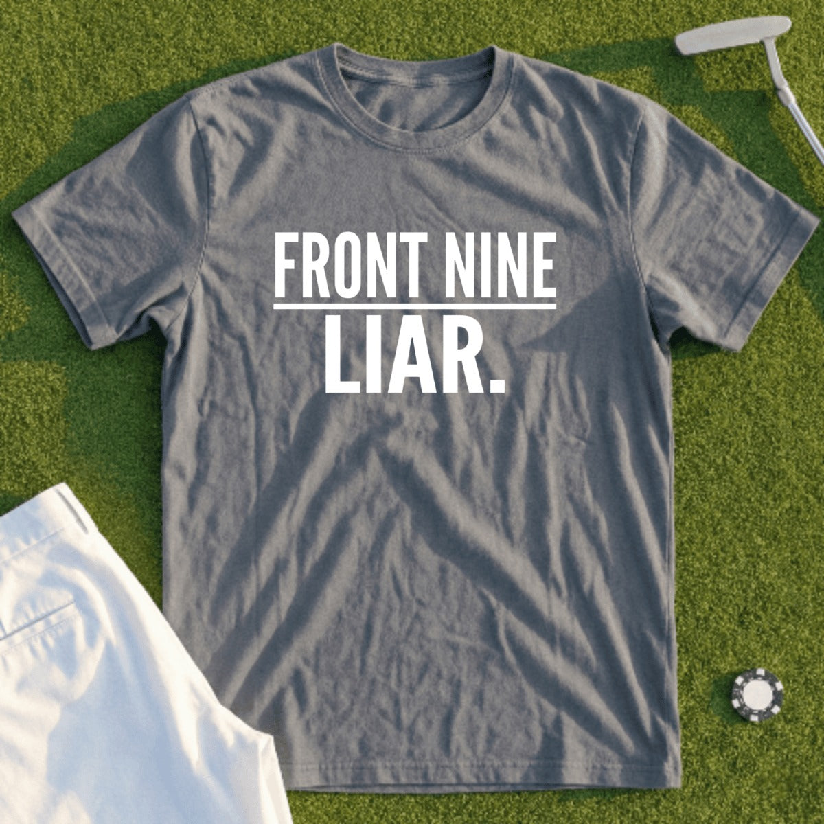Grey t-shirt with "FRONT NINE LIAR." text, folded with golf tee.