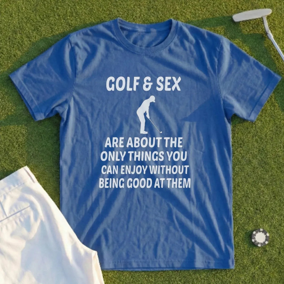 Blue t-shirt with text about golf and sex, on a grassy surface.