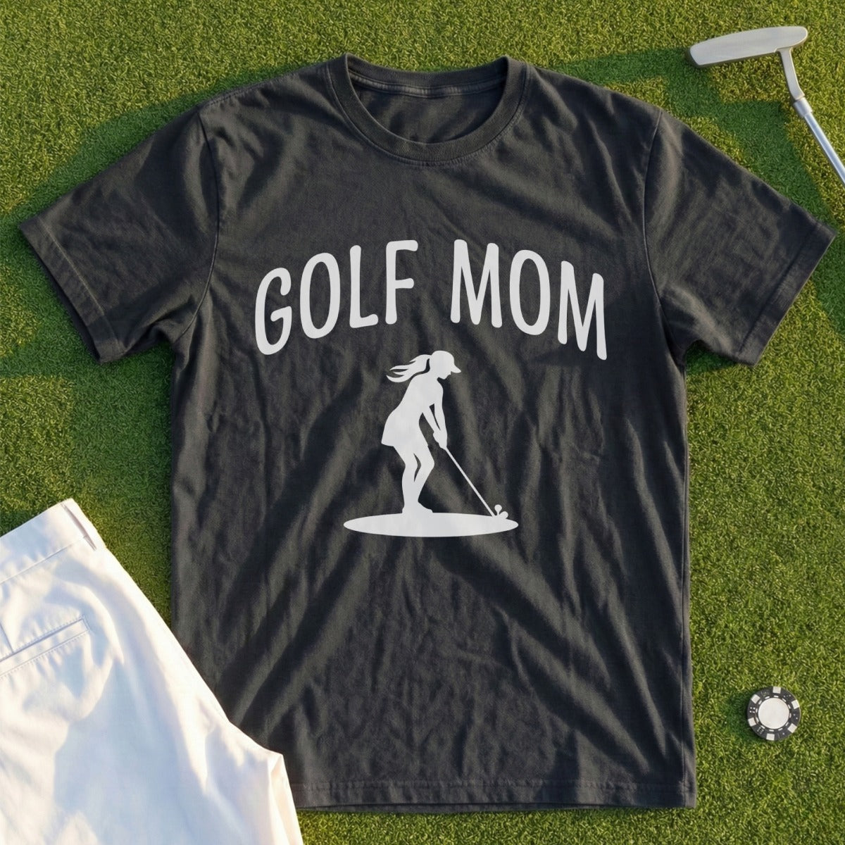Black t-shirt with "Golf Mom" and a golfer graphic, on grass.