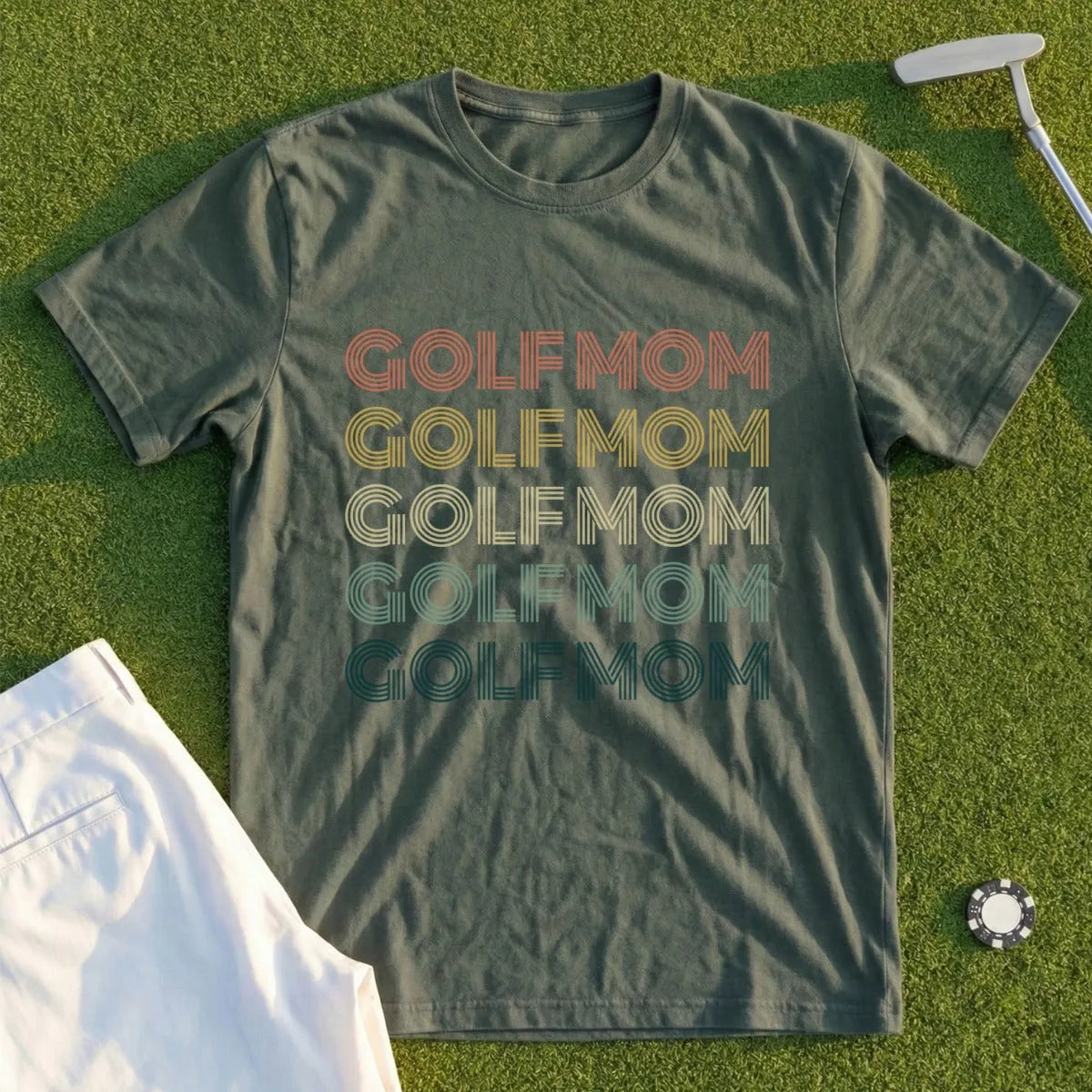 Green t-shirt with "GOLFMOM" repeated in retro rainbow stripes.