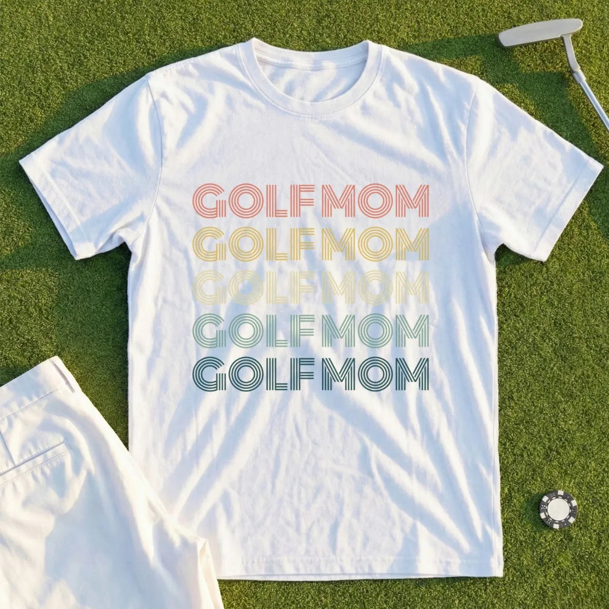 White t-shirt with "GOLF MOM" printed in colorful retro lettering.