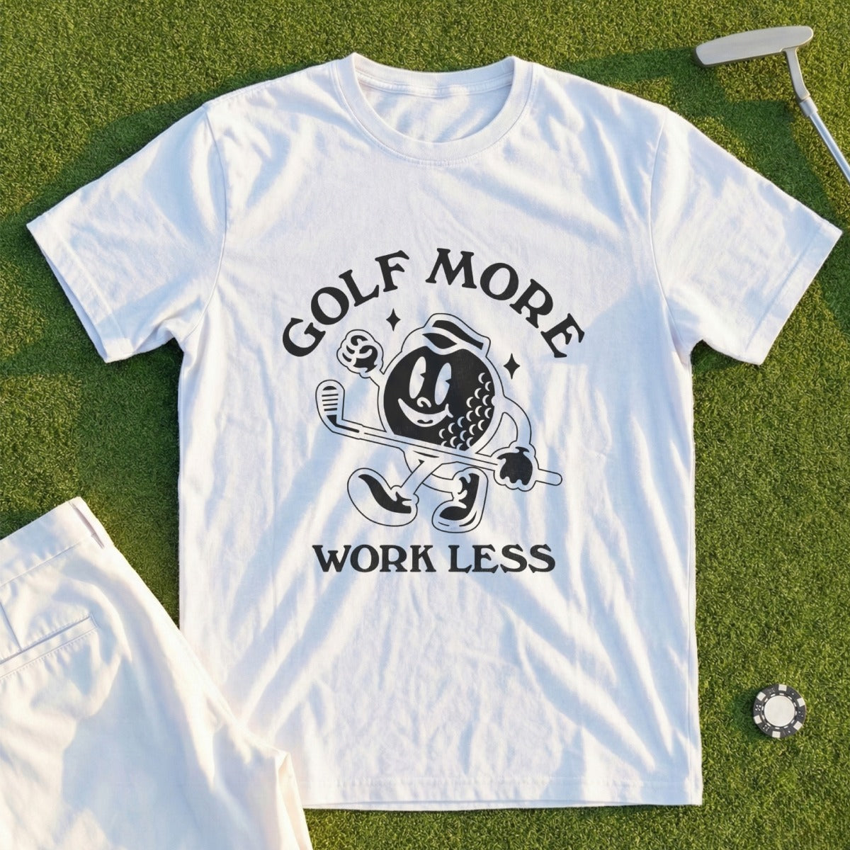 White t-shirt with "Golf More Work Less" graphic and cartoon golf ball character.