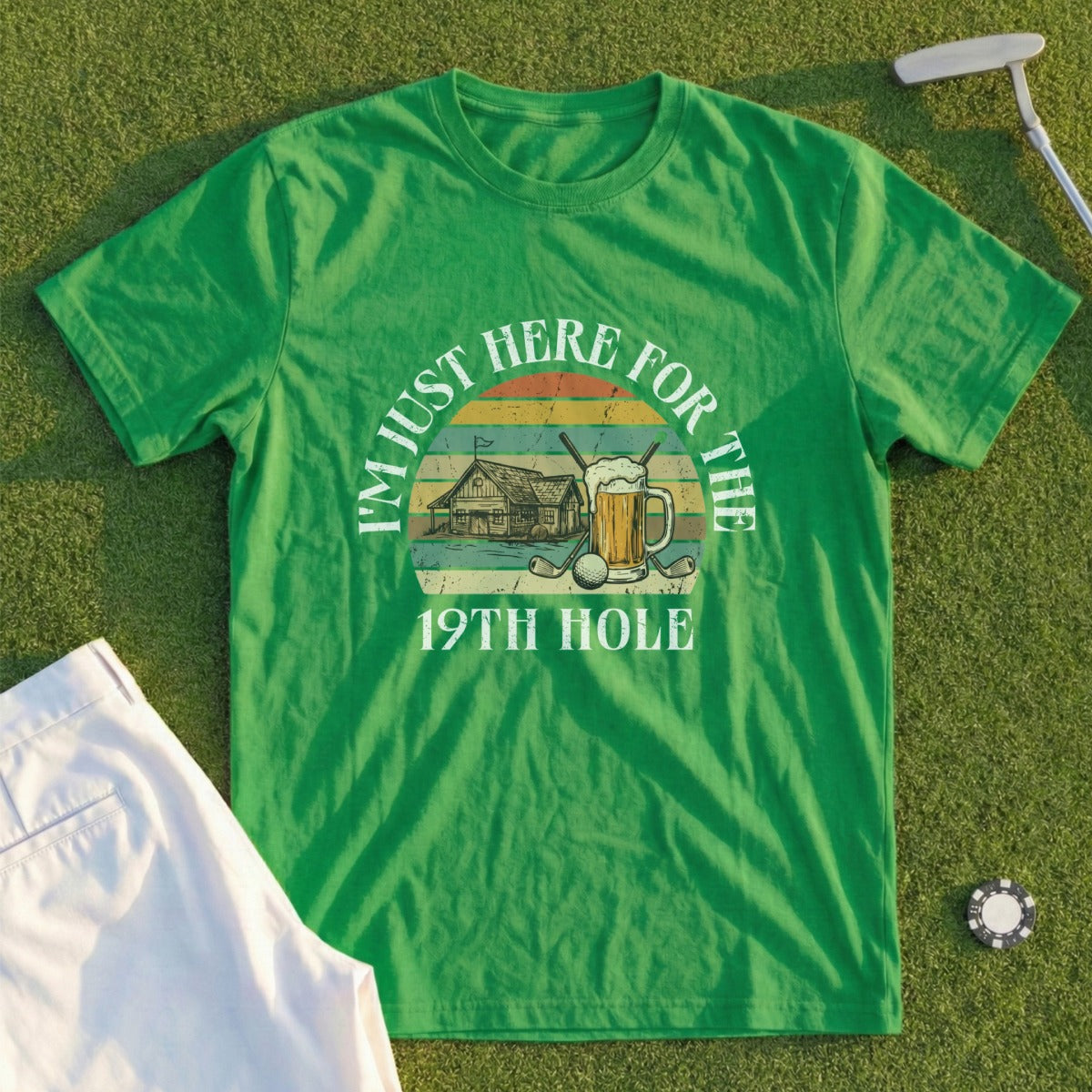 Green t-shirt with "I'M JUST HERE FOR THE 19TH HOLE" text and golf imagery.