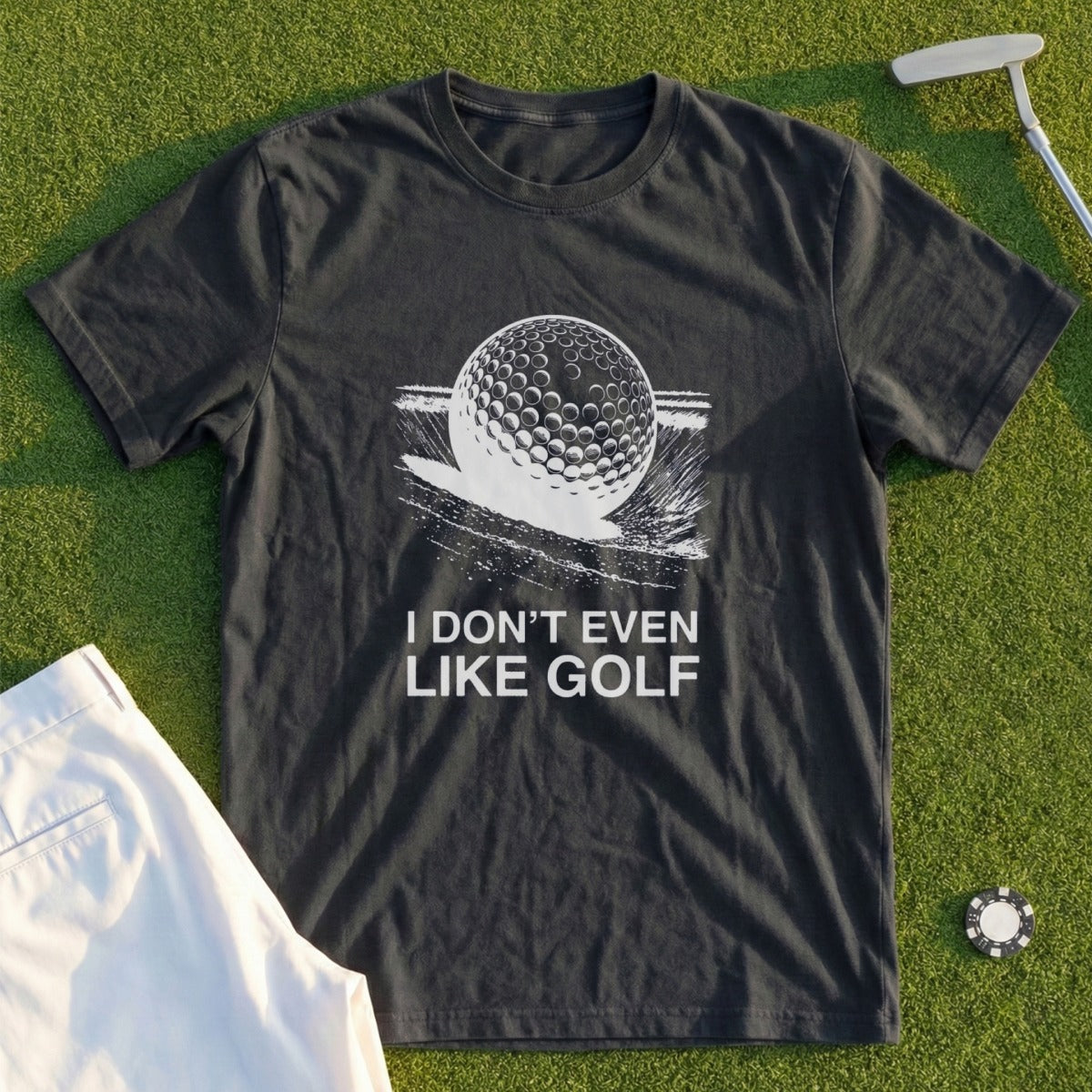 Dark t-shirt with white graphic of a golf ball on water and text "I DON'T EVEN LIKE GOLF".