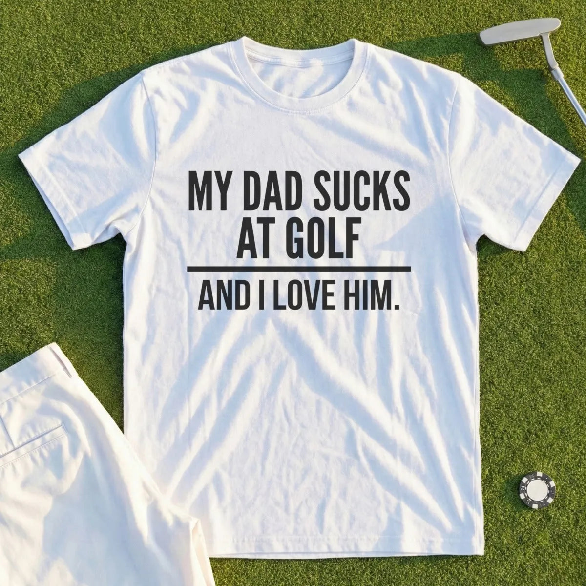 White t-shirt with black text "MY DAD SUCKS AT GOLF AND I LOVE HIM."
