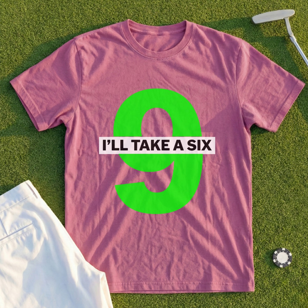 Pink t-shirt with "I'LL TAKE A SIX" and large green nine on a golf course.