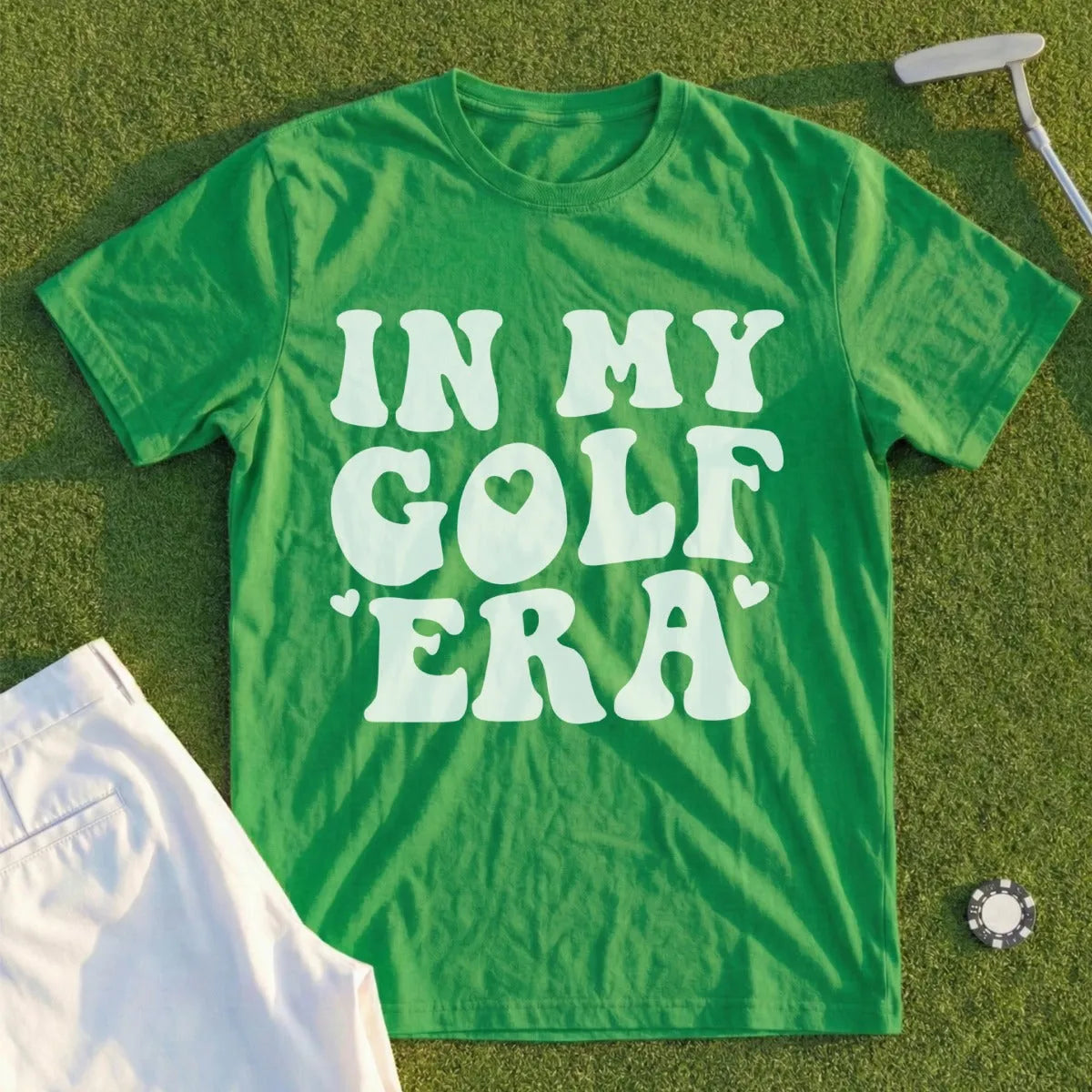 Green t-shirt with "In My Golf Era" text and golf accessories.
