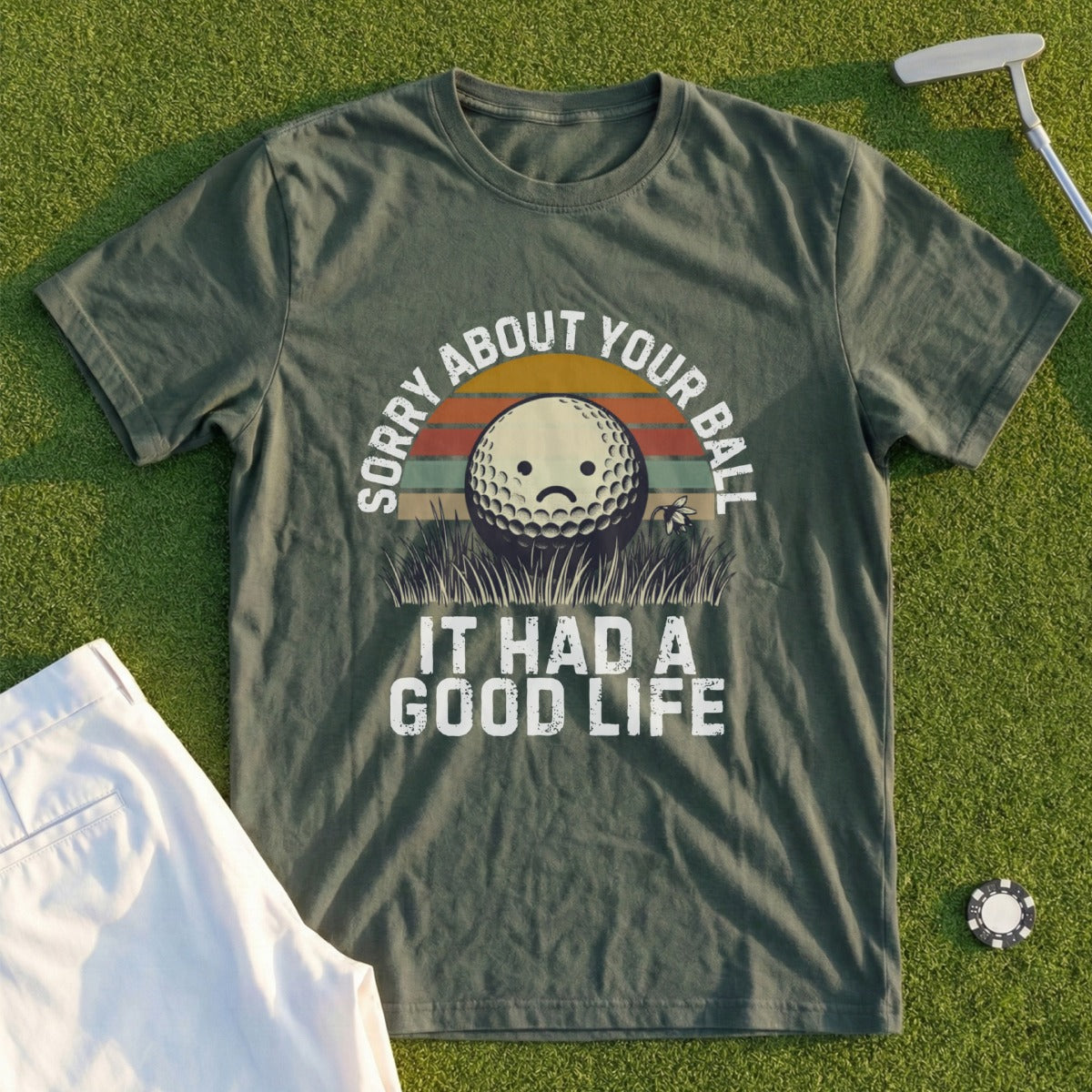 Green t-shirt with text "Sorry About Your Ball It Had a Good Life" and a sad golf ball graphic.