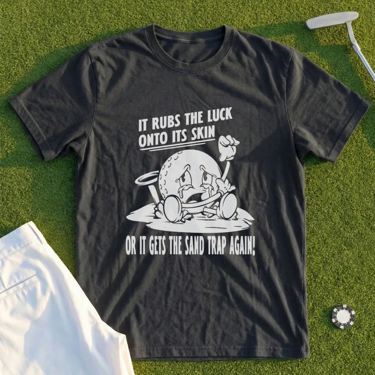 Dark t-shirt with cartoon golfer crying, "It rubs the luck onto its skin or it gets the sand trap again!".