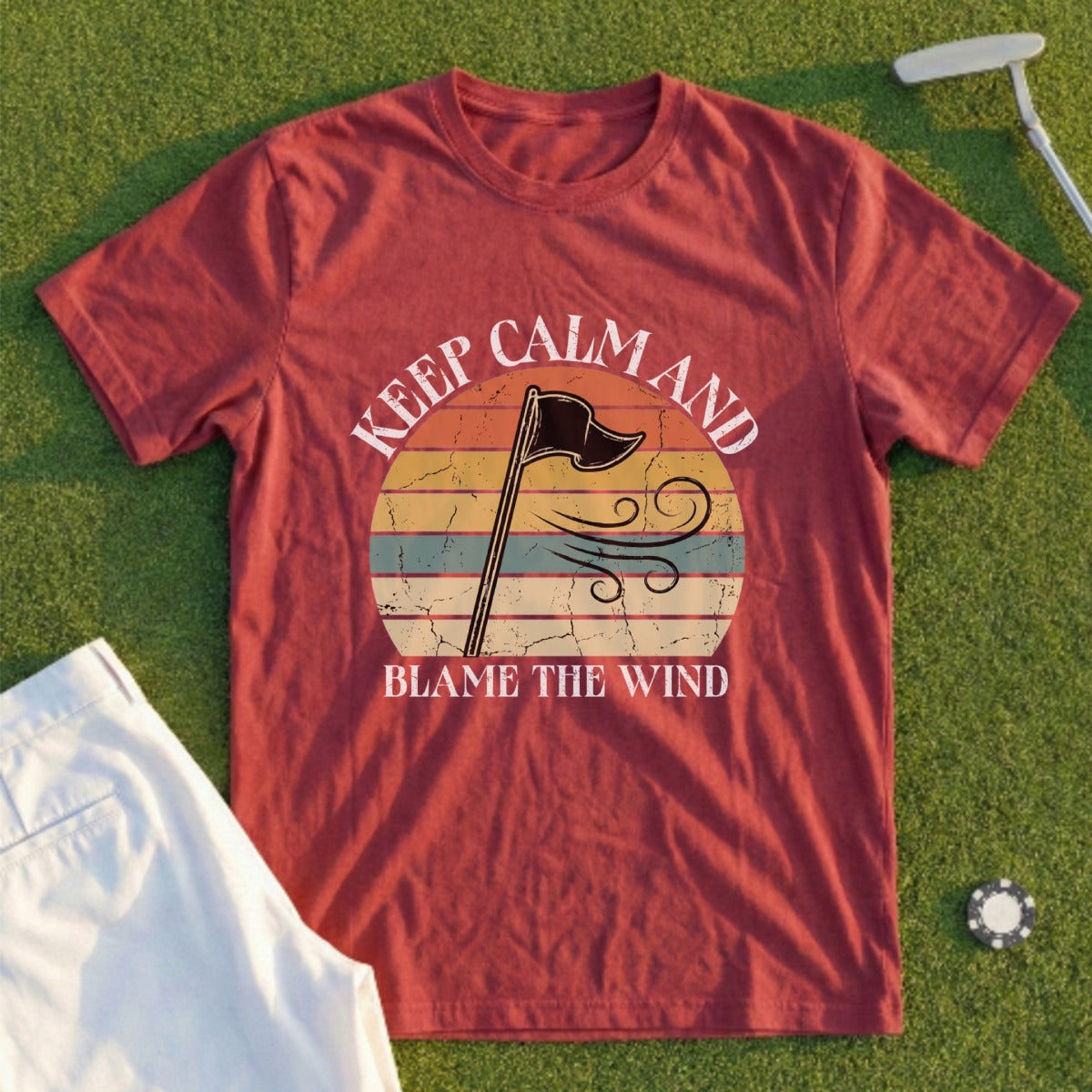 Red t-shirt with "Keep Calm and Blame the Wind" text and flag on sunset background.