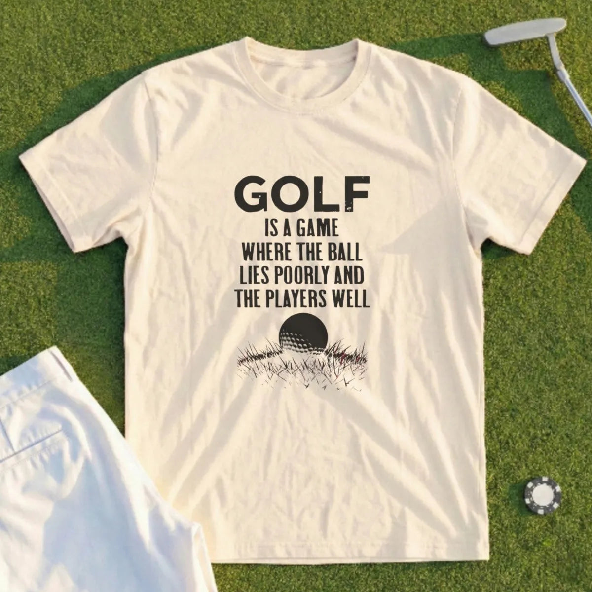 Cream t-shirt with "GOLF IS A GAME WHERE THE BALL LIES POORLY AND THE PLAYERS WELL" text and golf ball.