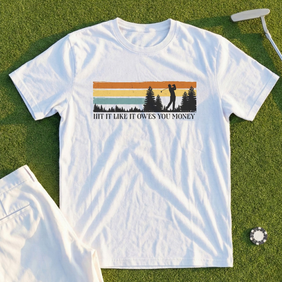 White t-shirt with golfer silhouette and "Hit it like it owes you money" text.