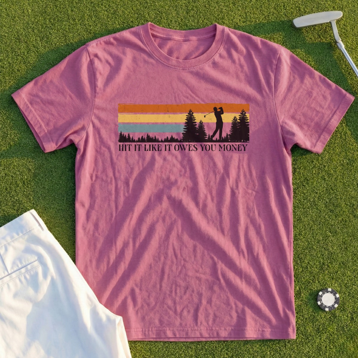 "Hit It Like It Owes You Money" text on a purple t-shirt with a golf scene.
