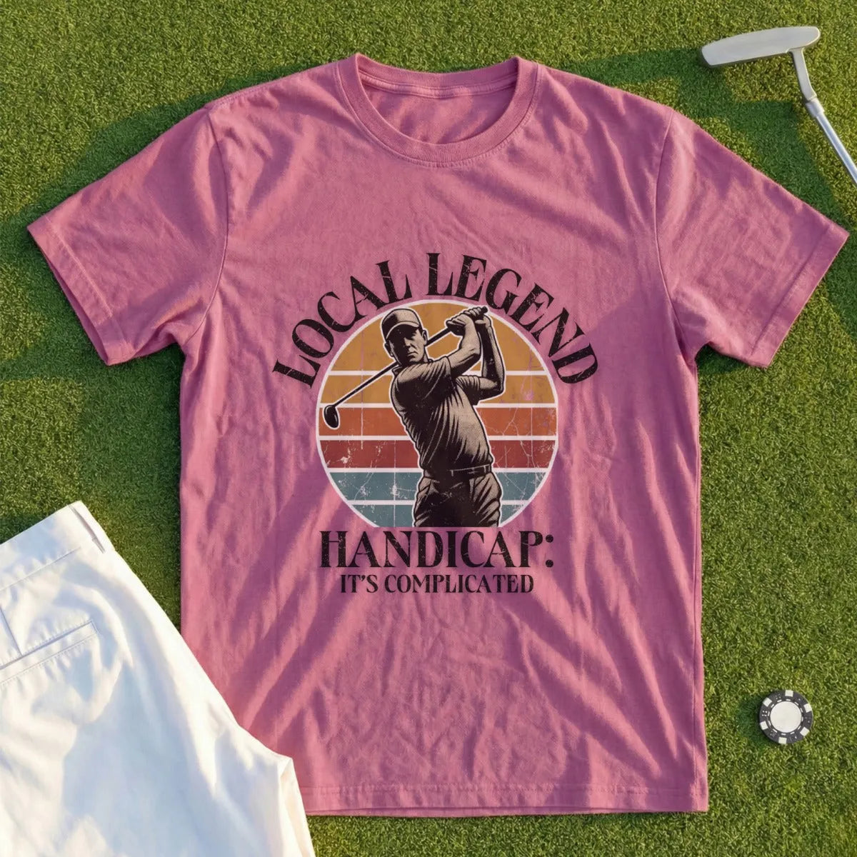 Pink t-shirt with graphic of a golfer and text "LOCAL LEGEND HANDICAP: IT'S COMPLICATED".