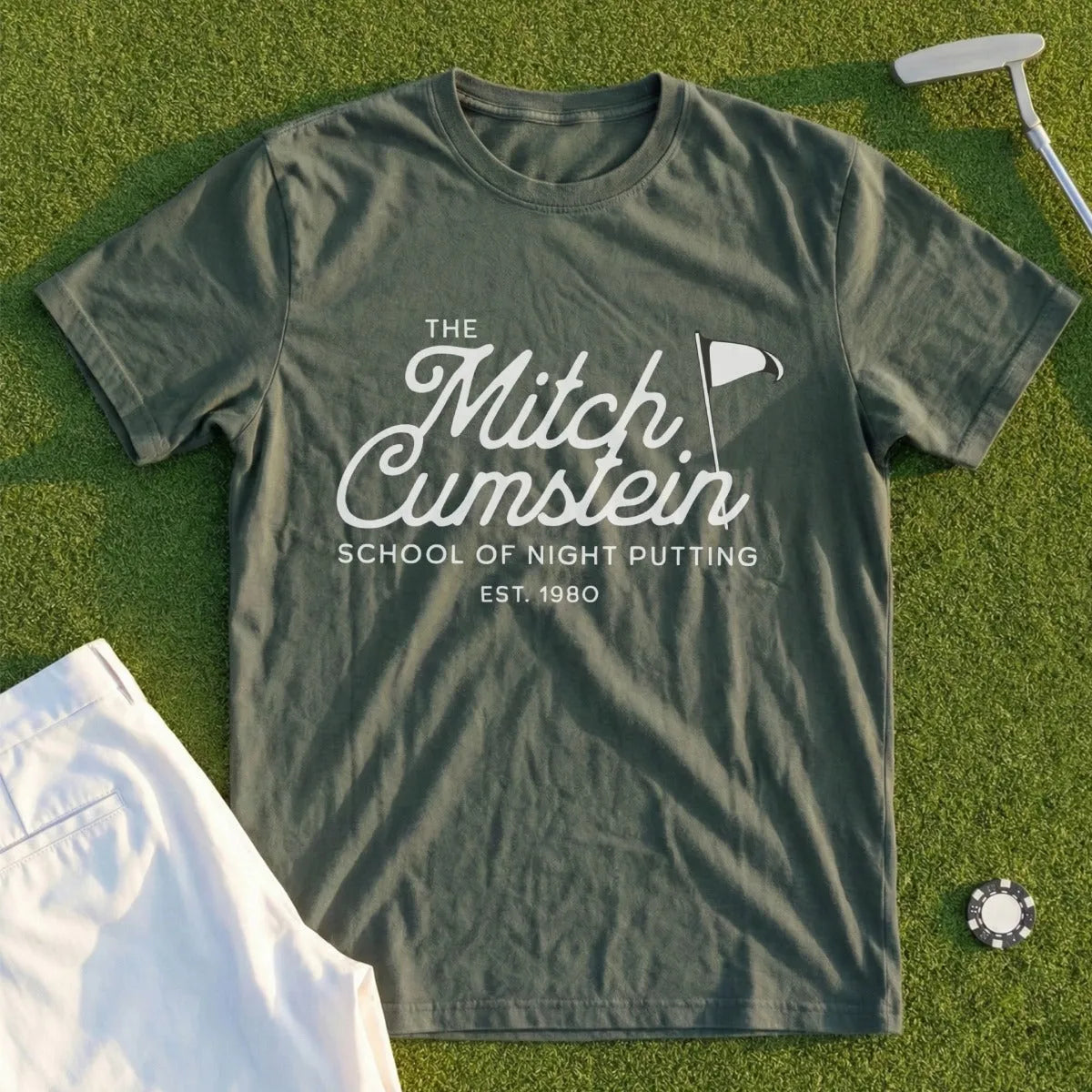 Olive t-shirt with "Mitch Cumstein School of Night Putting Est. 1980" text and golf imagery.