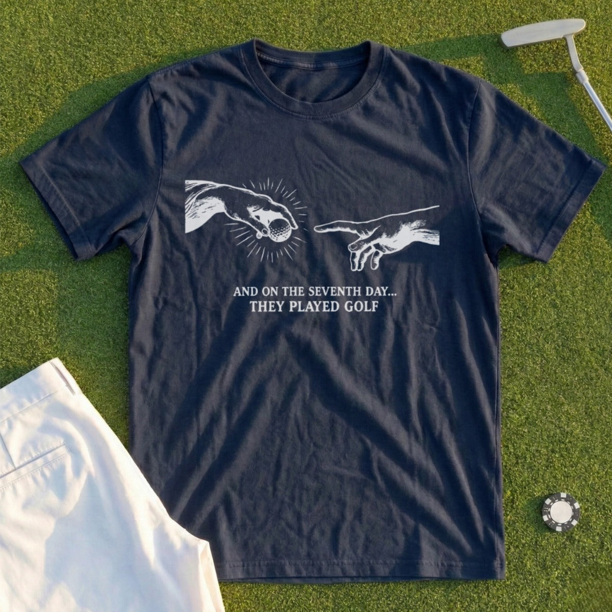 Dark t-shirt with "The Creation of Adam" inspired graphic and text about golf.
