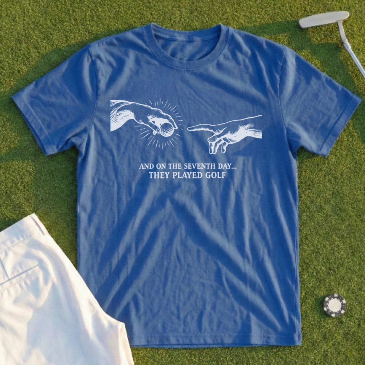 Blue t-shirt with golf graphic and text "AND ON THE SEVENTH DAY... THEY PLAYED GOLF".