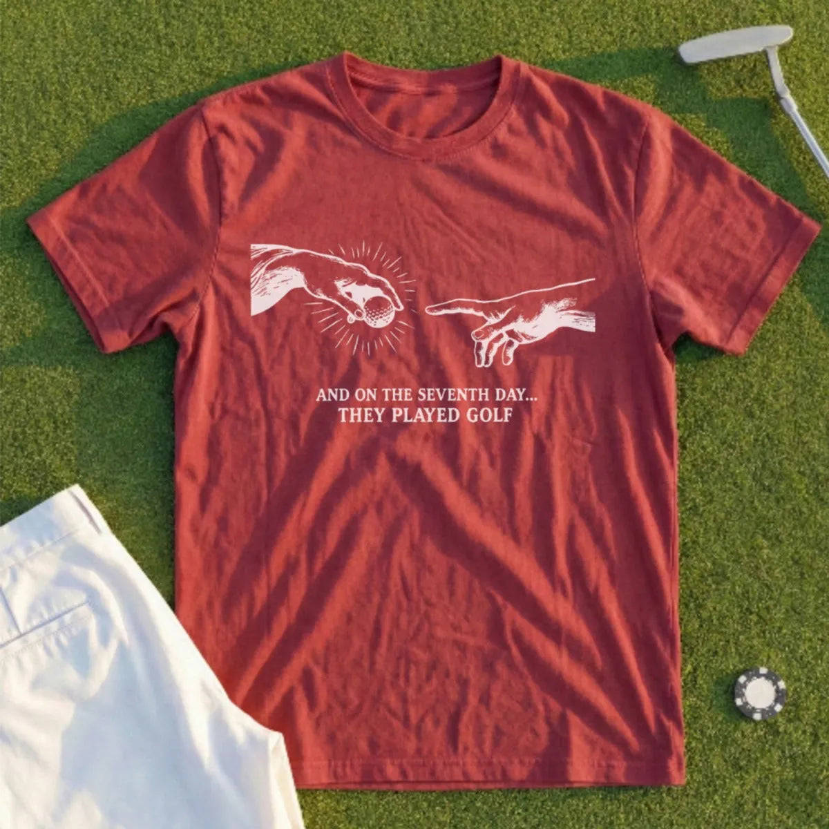 Red t-shirt with "And on the seventh day... they played golf" text and Michelangelo's Creation of Adam hands.