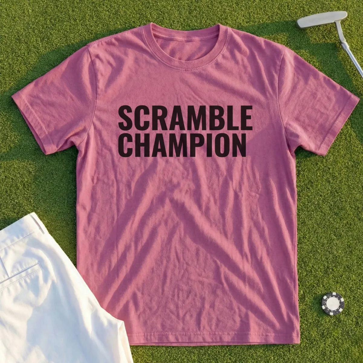 Mauve t-shirt with black text "Scramble Champion" on a golf course.