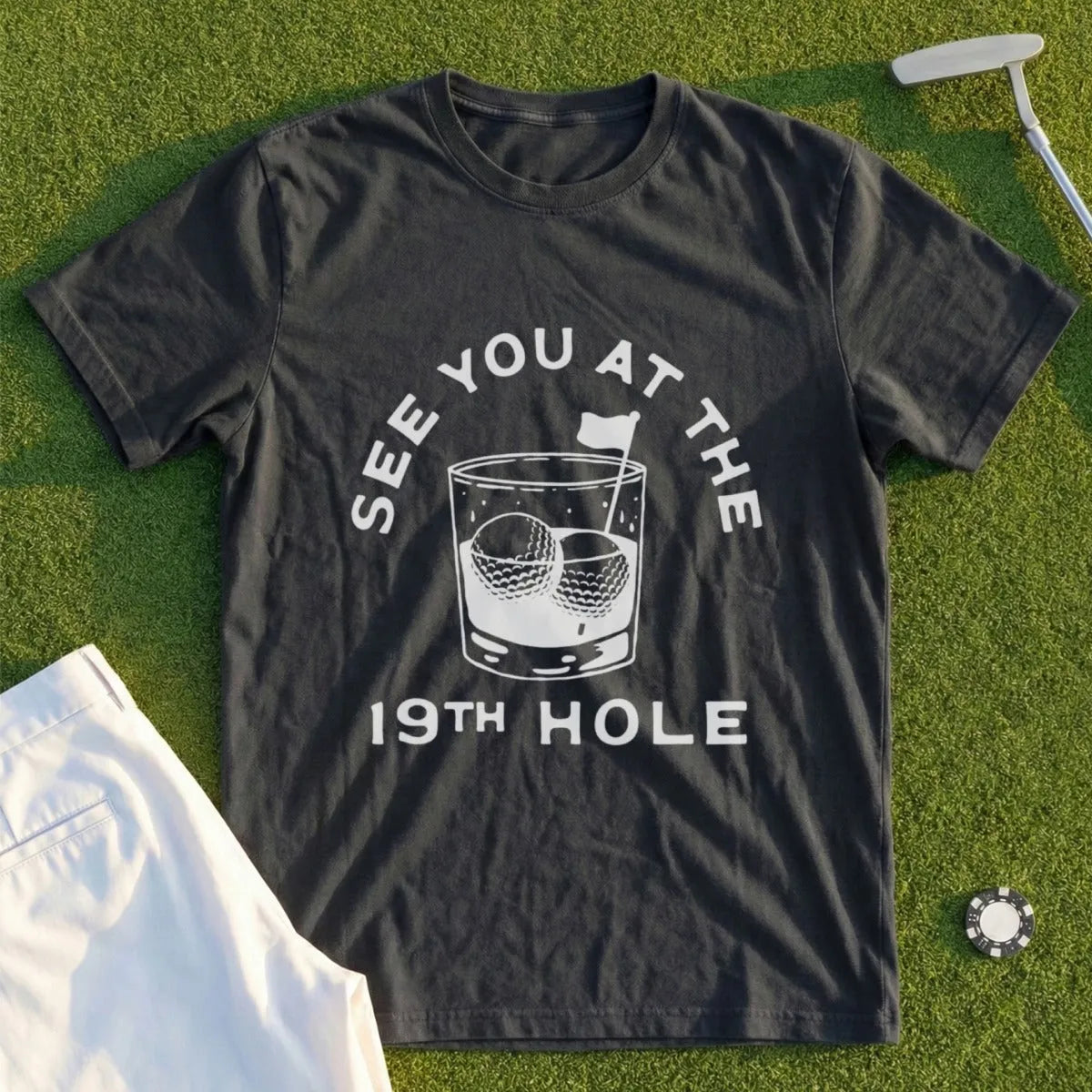 Dark t-shirt with "See you at the 19th hole" and golf balls in a whiskey glass.