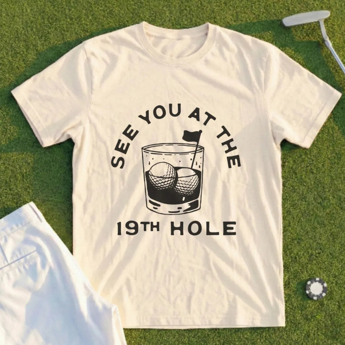 Cream t-shirt with "See You at the 19th Hole" text and golf balls in a glass.