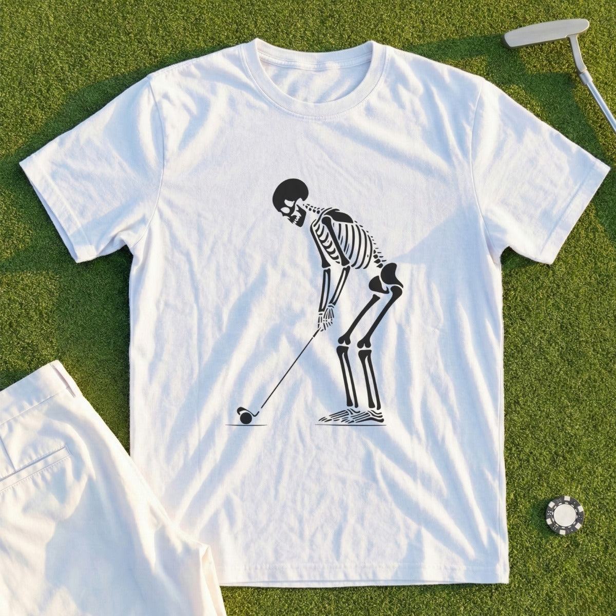 White t-shirt with a skeleton golfing graphic, next to golf shorts.