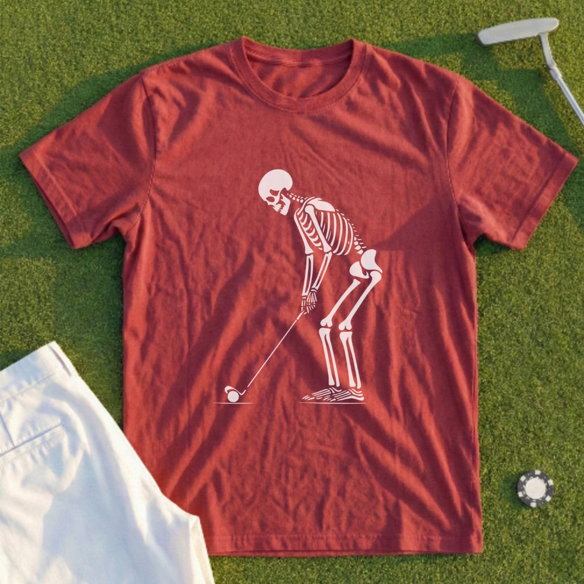 Skeleton golfing on a red t-shirt with white shorts and golf ball.