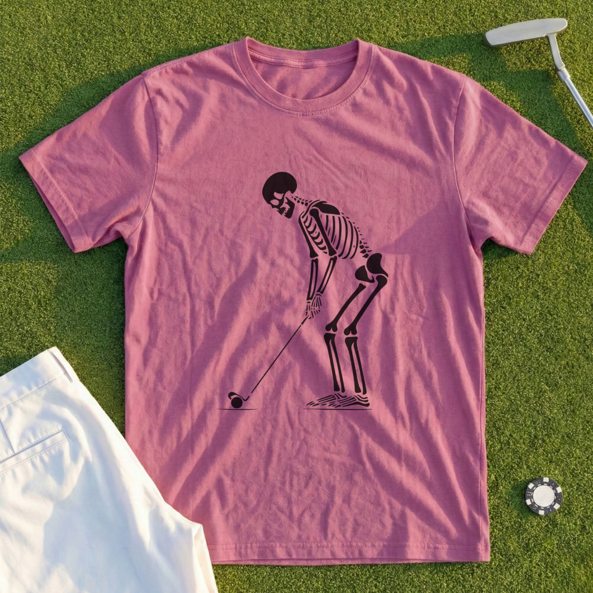 Pink t-shirt with a skeleton golfing graphic and white golf shorts.