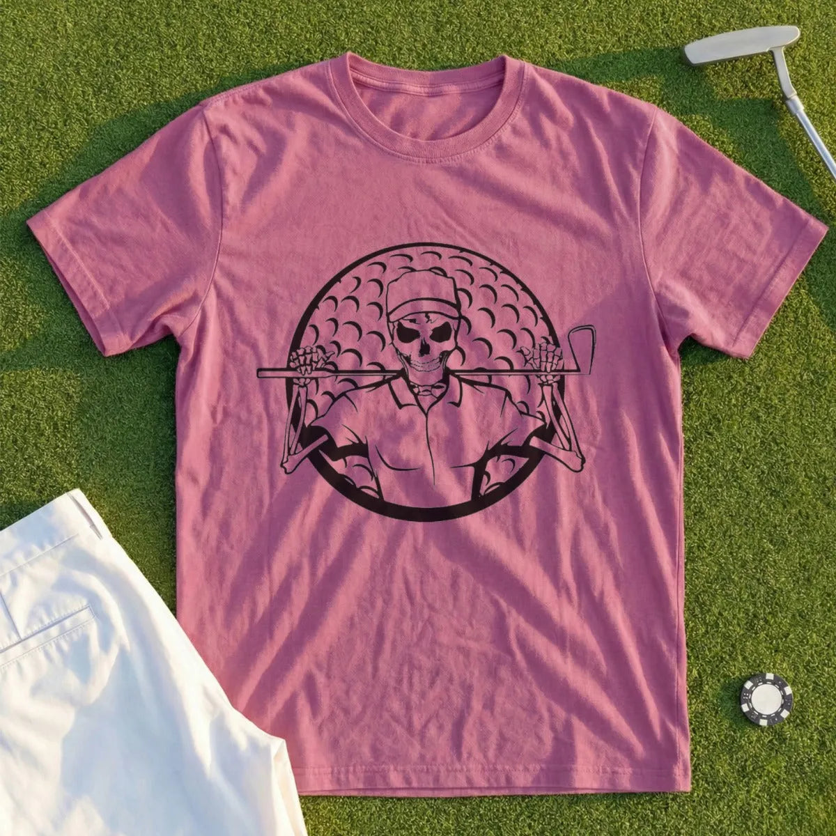 Skeleton golfer holding clubs in front of a golf ball on a pink t-shirt.