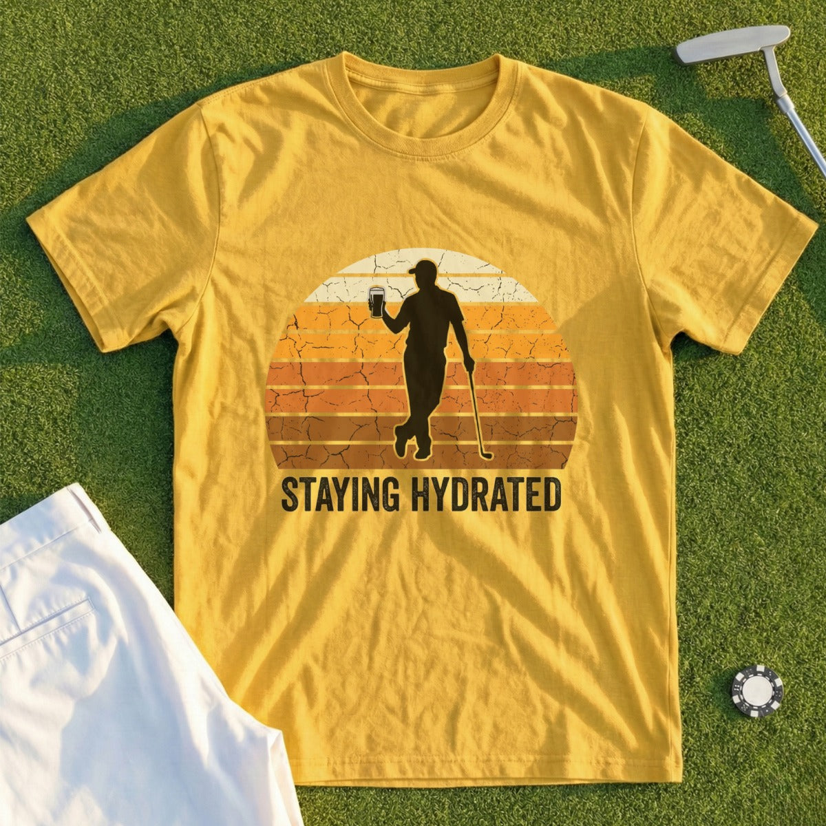 Yellow t-shirt with golfer silhouette and "STAYING HYDRATED" text at sunset.