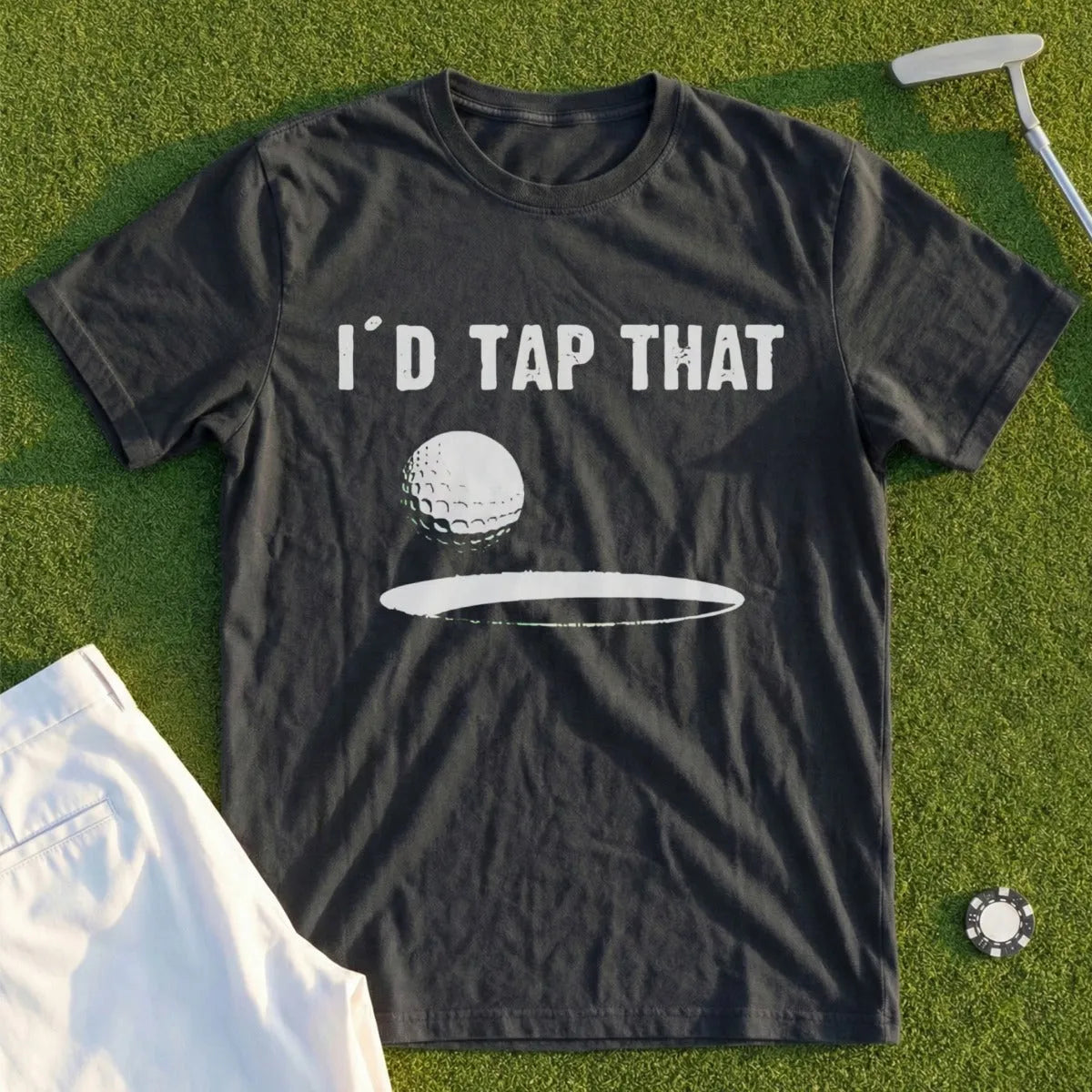 Dark t-shirt with "I'D TAP THAT" text and golf ball graphic on green grass.